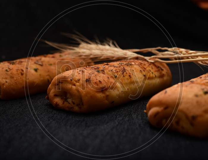 Bread Roll And Bunch Of Wheat On Black Background.