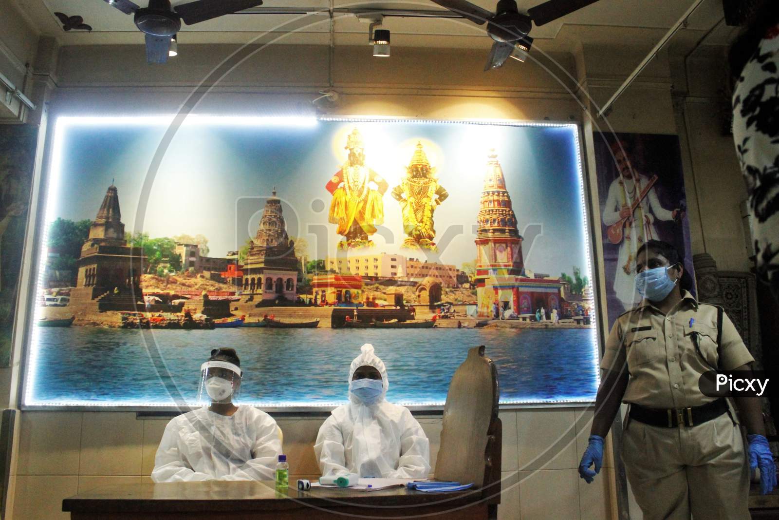 Healthcare workers wearing a Personal Protective Equipment (PPE) wait to screen people at a camp set up for the coronavirus disease (COVID-19),inside a temple in Mumbai, India on July 15, 2020.