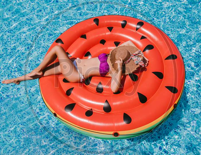 Woman Relaxing In Swimming Pool On Inflatable Pool Toy Outdoors