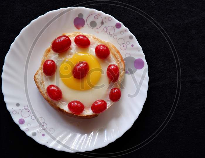 Homemade burger bun with fried egg and red cherries on a white plate . Top view image.
