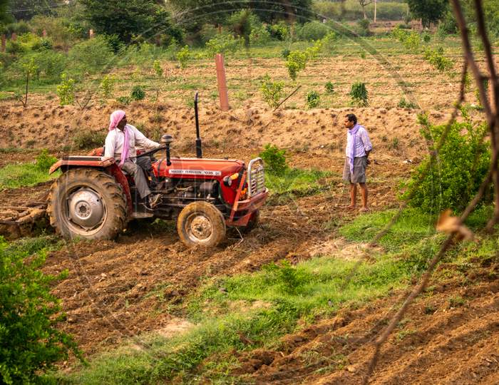 Farmers ploughing their lands using a tractor to prepare it for kharif crops during monsoon or after rain in Rajasthan