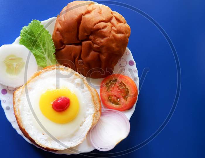 Homemade burger bun with fried egg and fresh vegetables on a white plate . Top view image.