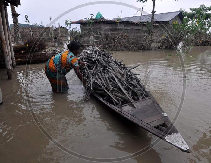 A woman collects firewood in the flood-affected area of Puthimari Village in Darrang, Assam on July 21, 2020
