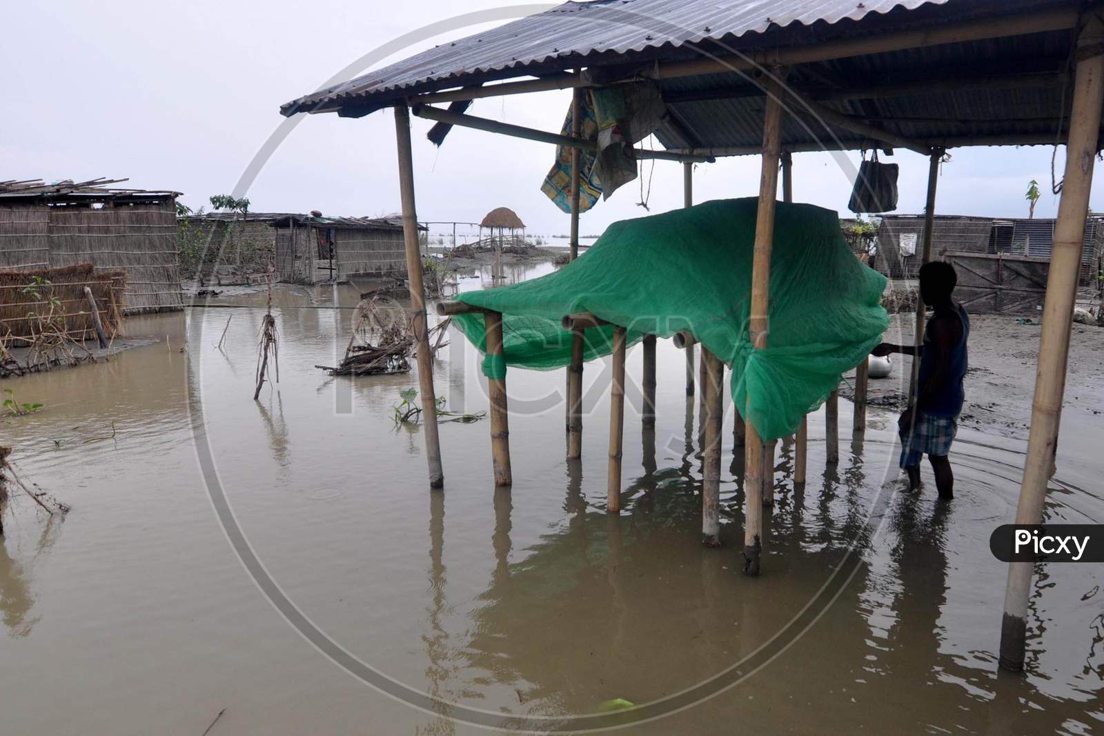 A villager stands in his hut which got damaged due to the flood at Puthimari village in Darrang, Assam on July 21, 2020
