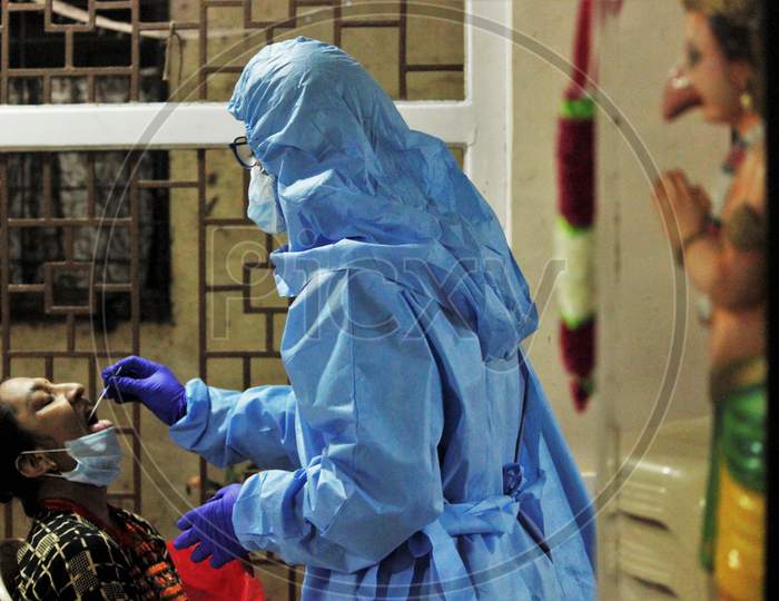 A health worker in personal protective equipment (PPE) collects a swab sample from a resident of a locality, at a camp set up for the coronavirus disease (COVID-19), inside a temple in  Mumbai, India on July 15, 2020.