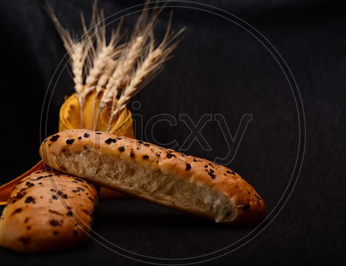Bread Roll And Bunch Of Wheat On Black Background.