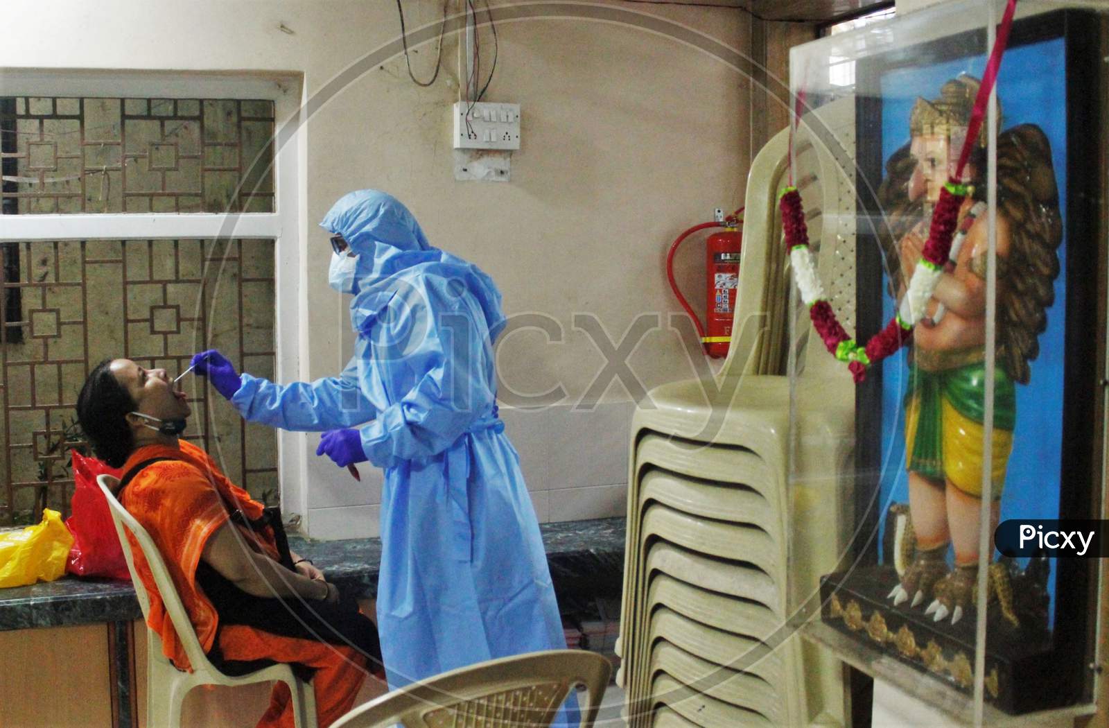 A health worker in personal protective equipment (PPE) collects a swab sample from a resident of a locality, at a camp set up for the coronavirus disease (COVID-19), inside a temple in  Mumbai, India on July 15, 2020.