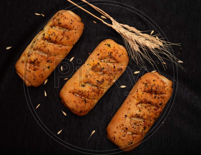 Bread Roll And Bunch Of Wheat On Black Background.Bread Roll And Bunch Of Wheat On Black Background.