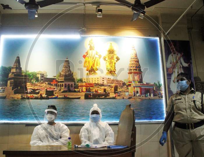 Healthcare workers wearing a Personal Protective Equipment (PPE) wait to screen people at a camp set up for the coronavirus disease (COVID-19),inside a temple in Mumbai, India on July 15, 2020.