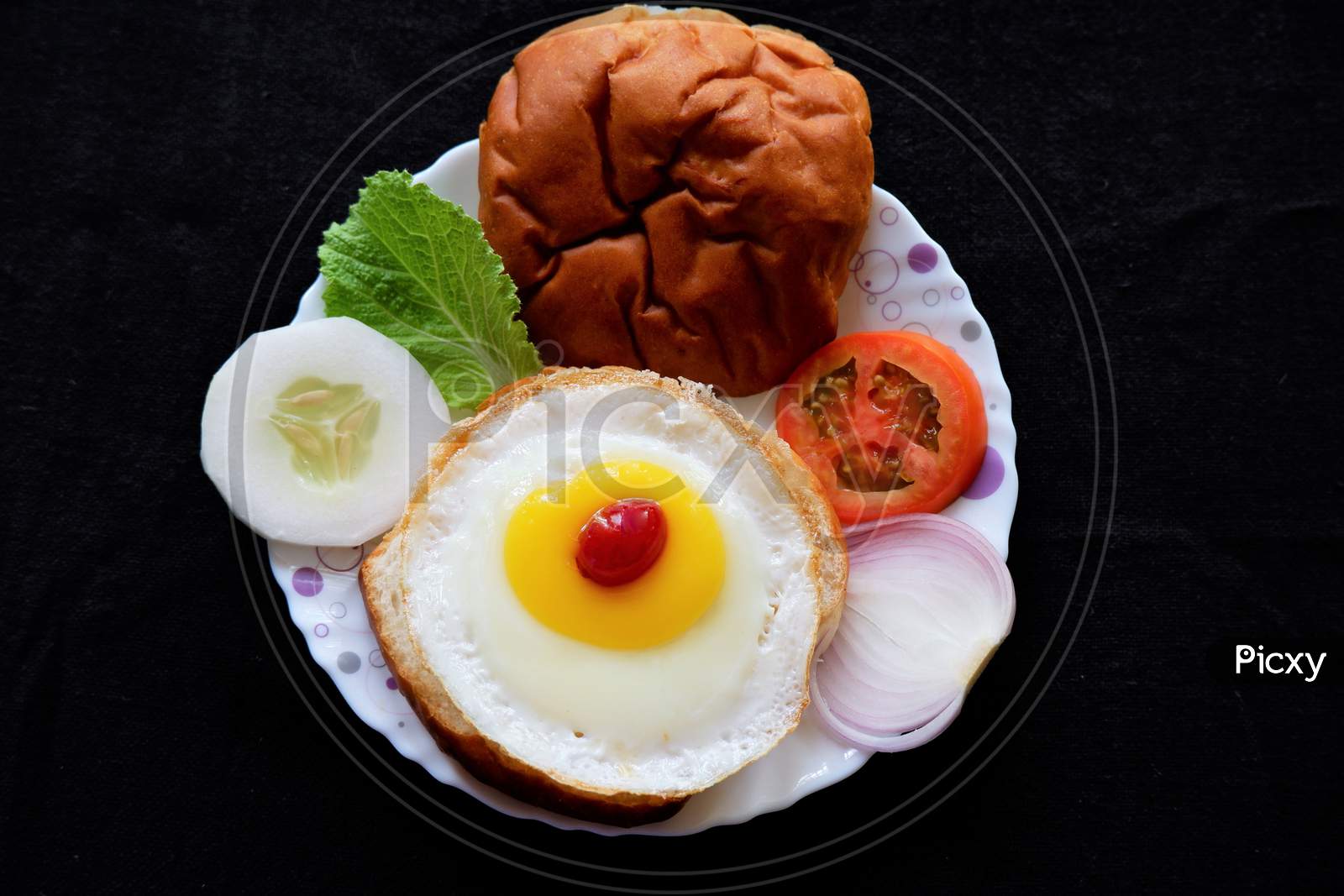 Homemade burger bun with fried egg and fresh vegetables on a white plate . Top view image.