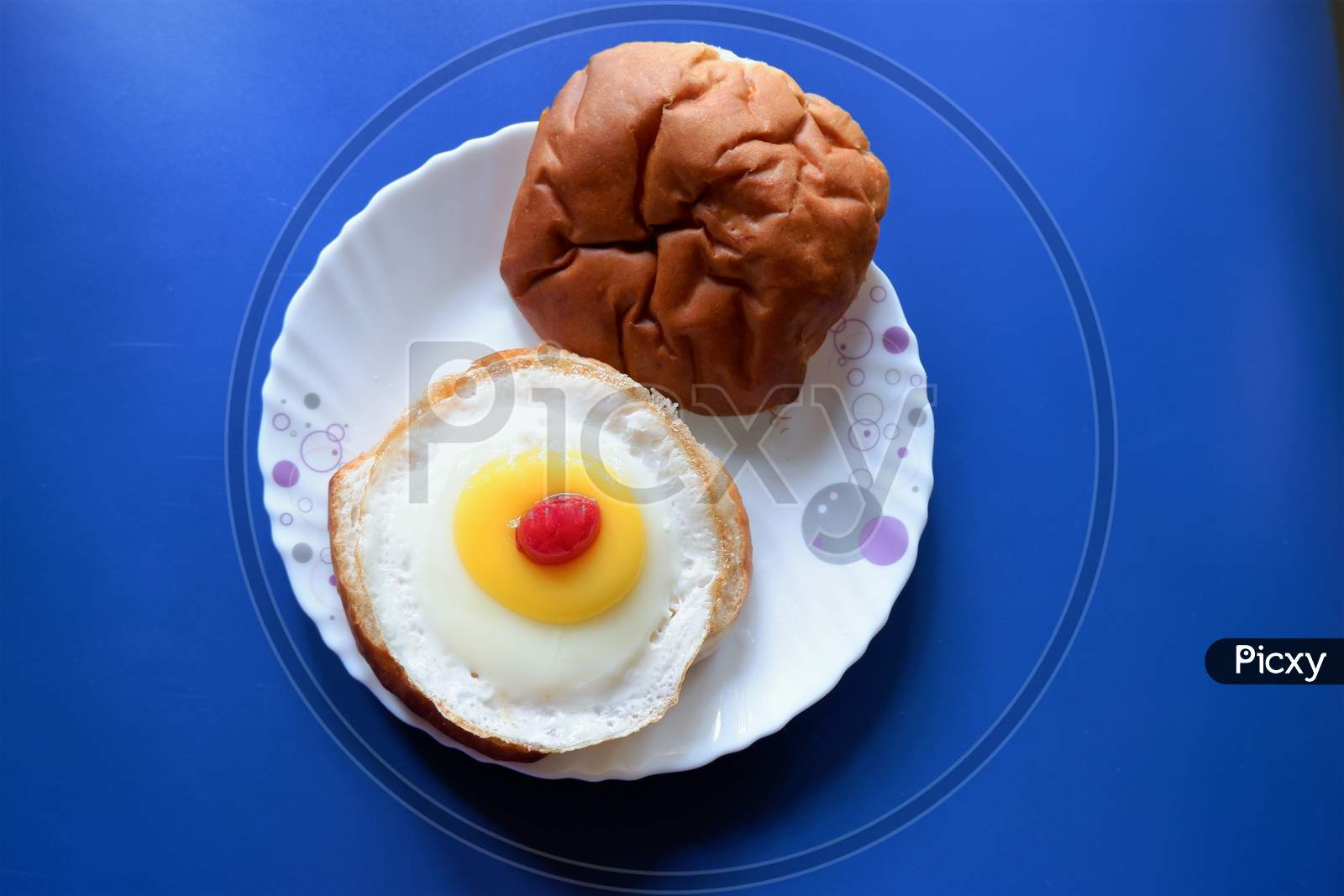Homemade burger bun with fried egg on a white plate . Top view image.