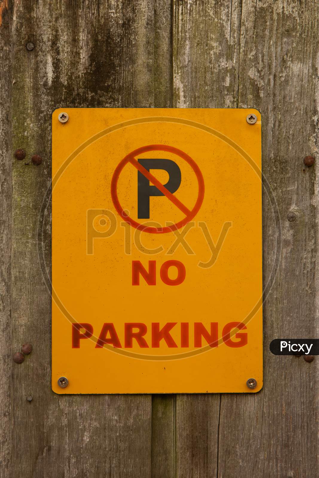 Yellow No Parking Sign On A Weathered Wooden Fence