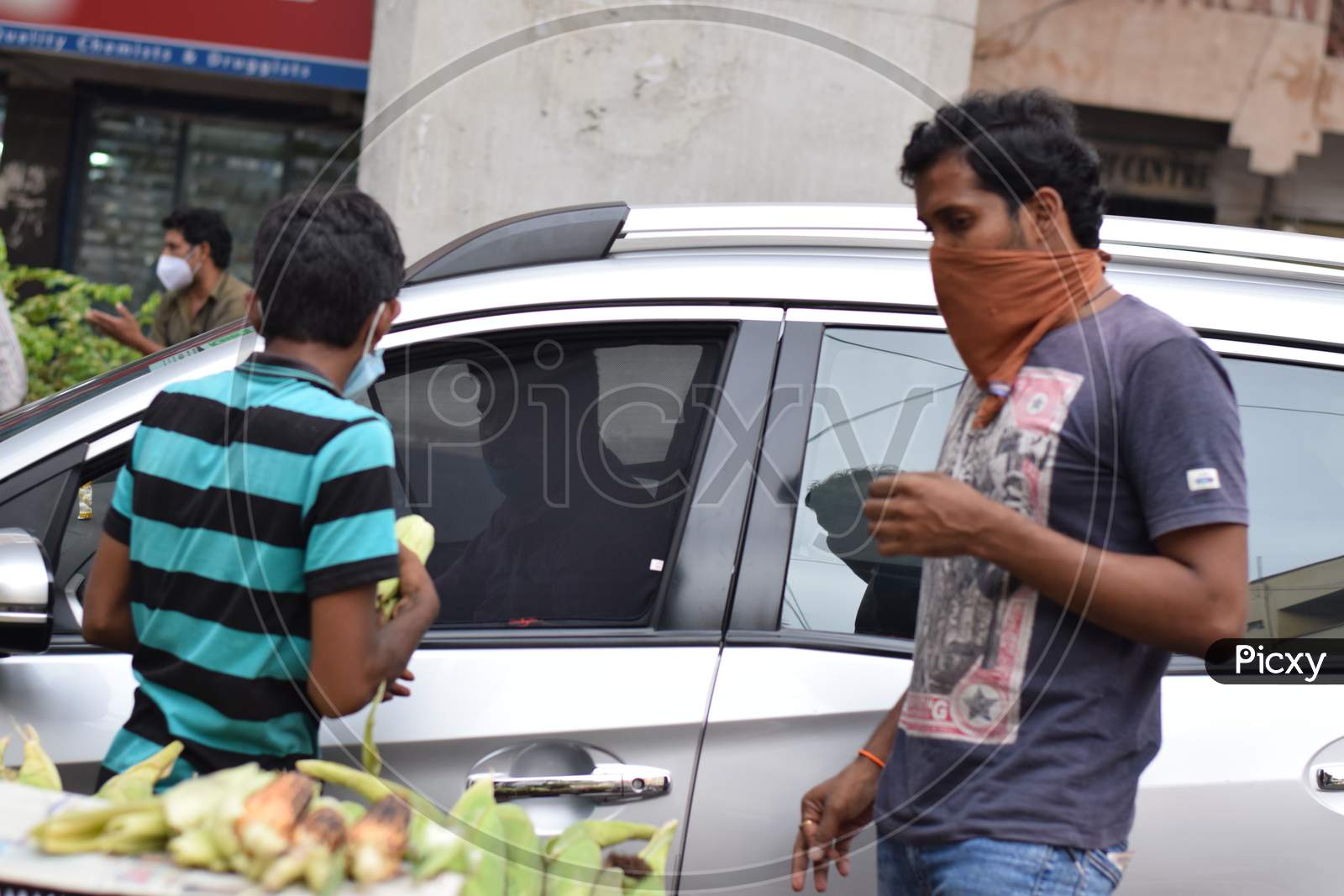 Hyderabad, Telangana, India. July-20-2020: Roasted Corn, People Are Doing Their Work Wearing Face Mask, The Person Going In The Car Is Buying A Mask