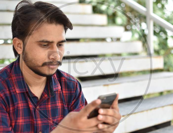 indian boy playing mobile phone ,sitting on stair