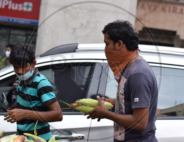 Hyderabad, Telangana, India. July-20-2020: Roasted Corn, People Are Doing Their Work Wearing Face Mask, The Person Going In The Car Is Buying A Mask