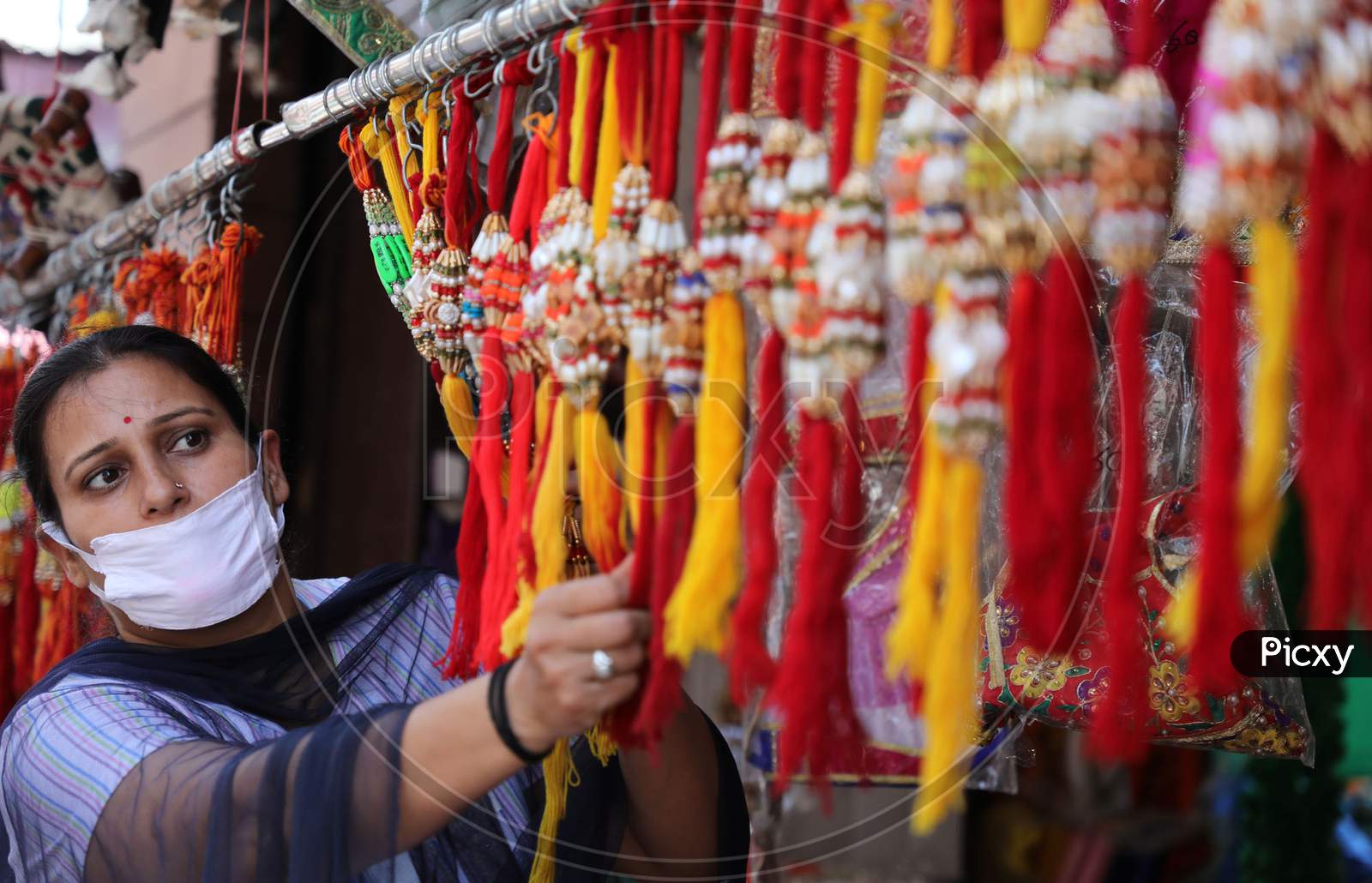 A woman buys rakhi, a bracelet made of thread ahead of the Raksha Bandhan, a festival which celebrates the bond between brothers and sisters in Jammu on July 22, 2020