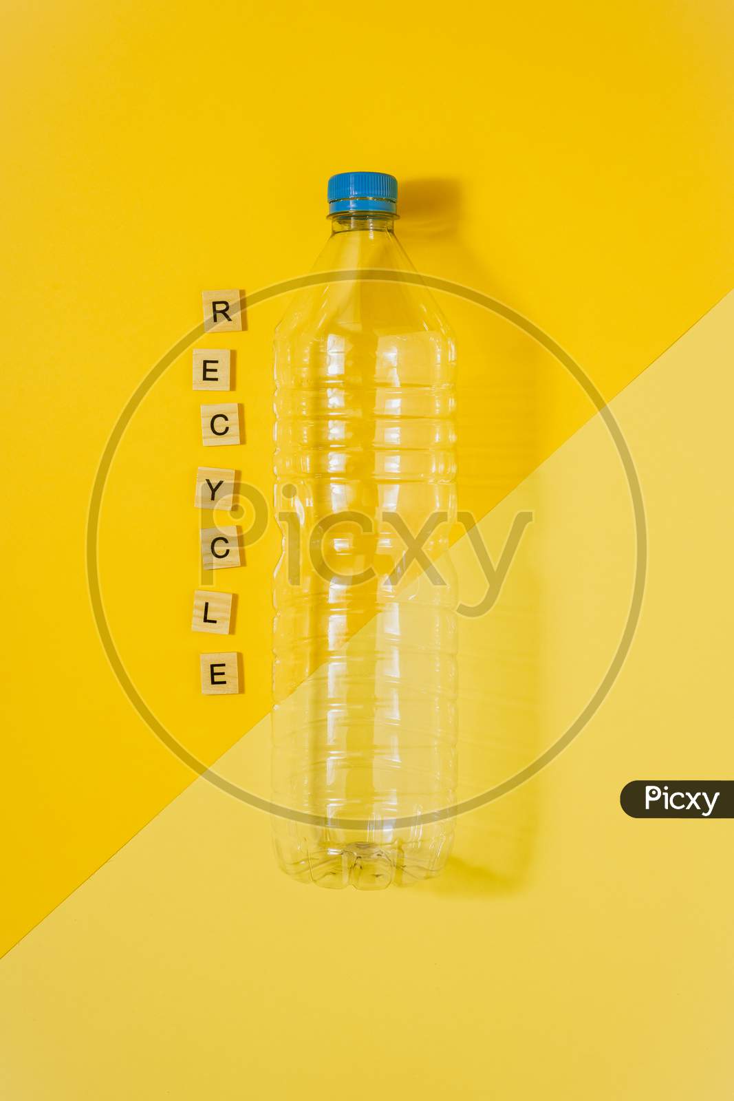 Clear Plastic Bottle With Blue Cap On A Yellow Background And The Word Recycle. Recycling And Environment Concept.