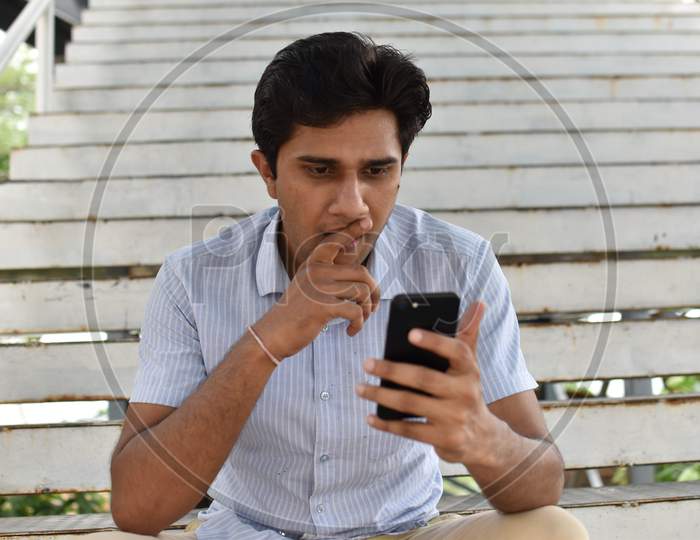 indian boy playing mobile phone ,sitting on stair