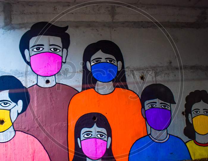 A Painting Done On A Wall To Create Awareness About Corona .It Tells Us To Wear Mask And Be Safe . The Whole Family Is Wearing Mask