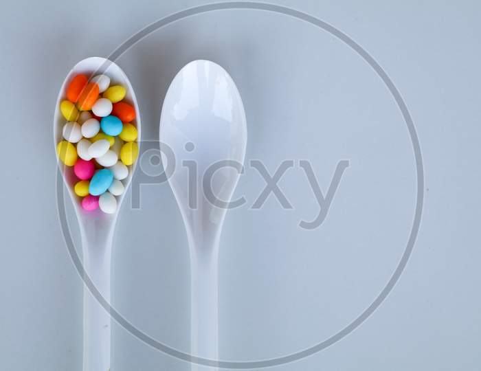 Multi Colored Fennel Sugar Candy In White Spoons Against White Background With Copy Space, Isolated