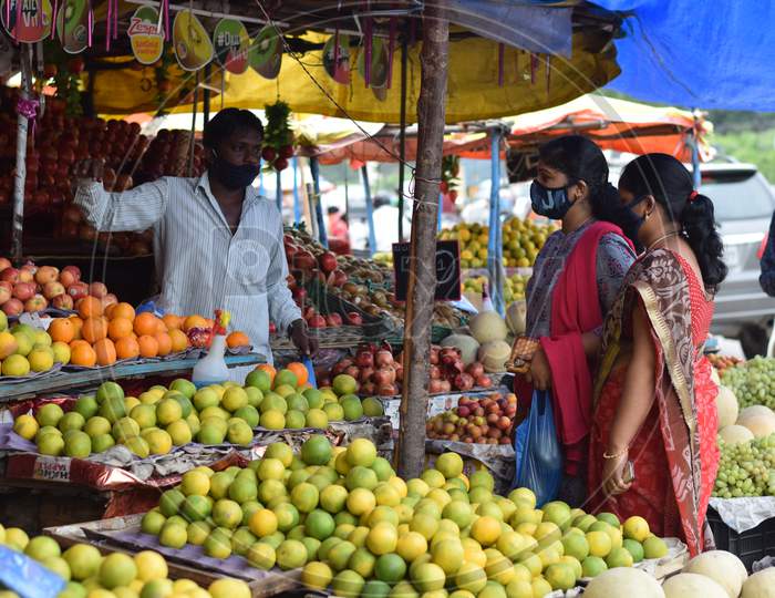 Hyderabad, Telangana, India. july-22-2020: fruits at road side, fruits trader selling fruits at road side while wearing face mask for protection from the coronavirus, corona pandemic time, peoples are wearing protective masks while buying fruits