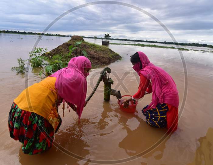 Two girls fetch water from a partially submerged hand pump at Madhab Para village in Nagaon, Assam on July 22, 2020