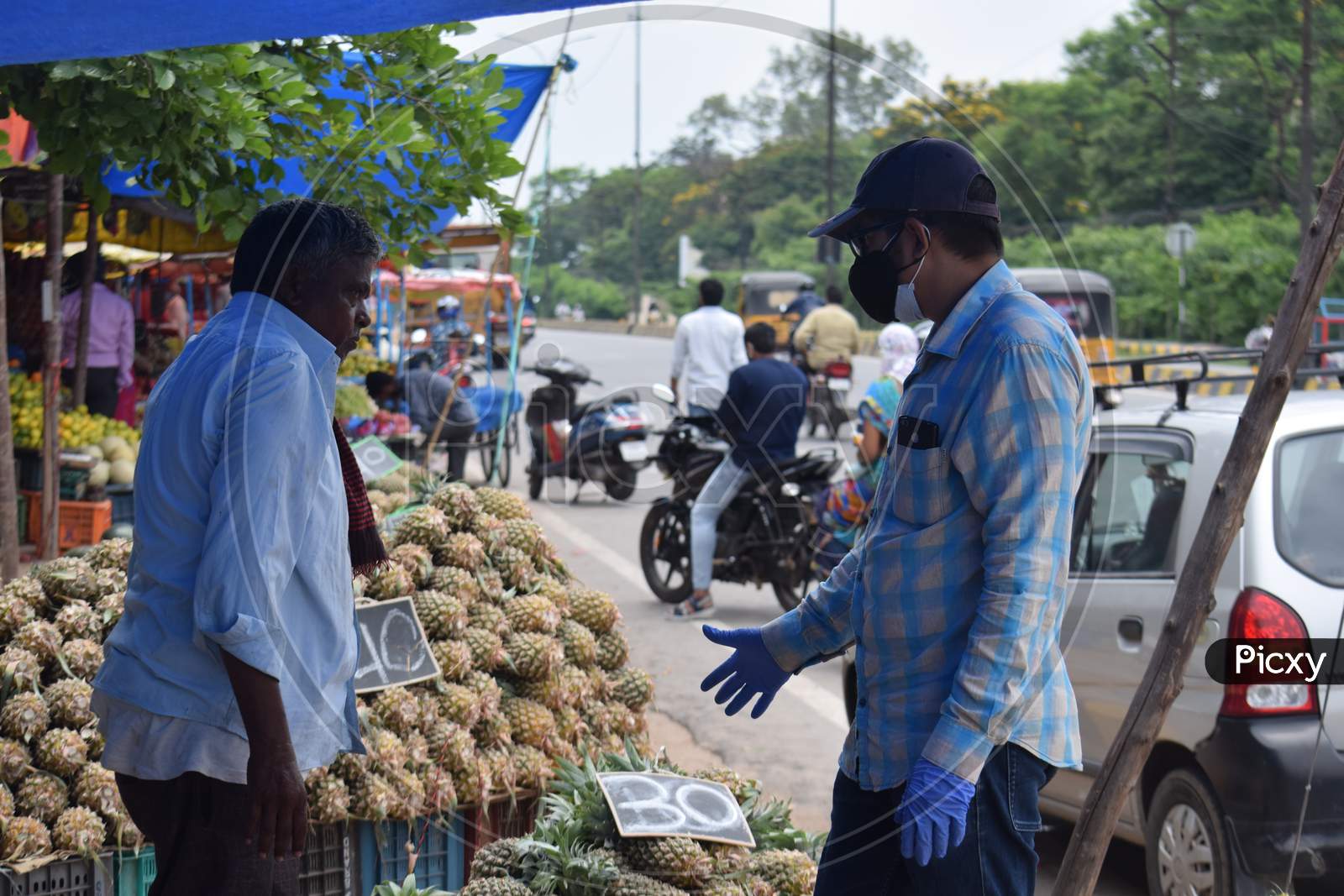 Hyderabad, Telangana, India. july-22-2020: fruits at road side, fruits trader selling fruits at road side while wearing face mask for protection from the coronavirus, corona pandemic time, peoples are wearing protective masks while buying fruits