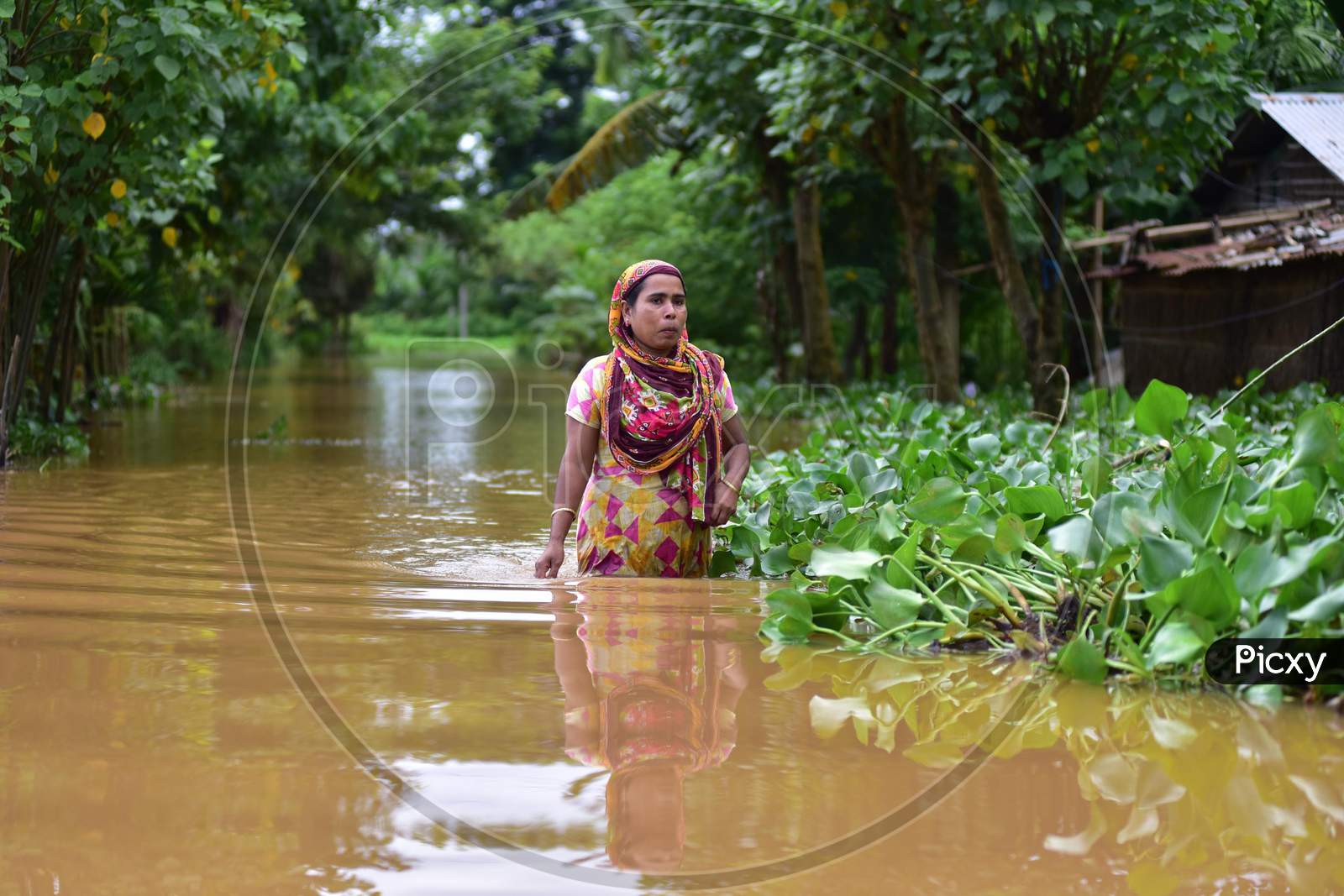 A woman wades through floodwaters in a flood-affected village in Nagaon, Assam on July 22, 2020