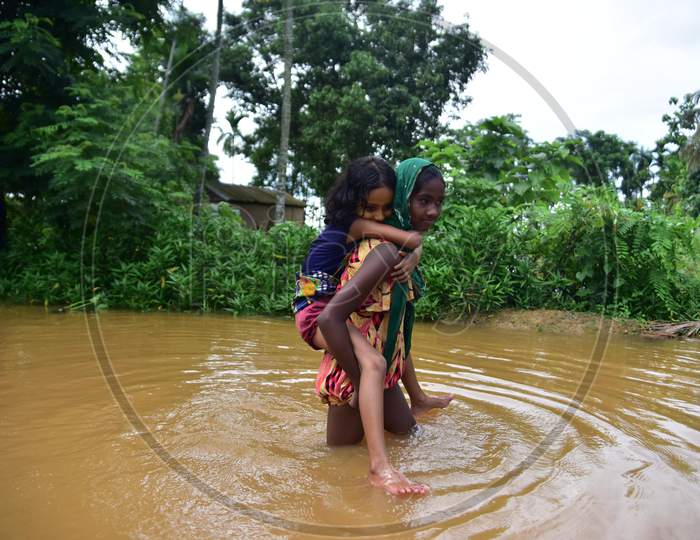 A girl carries another girl on her back as she wades through the floodwaters in the flood-affected village in Nagaon, Asam on July 22, 2020