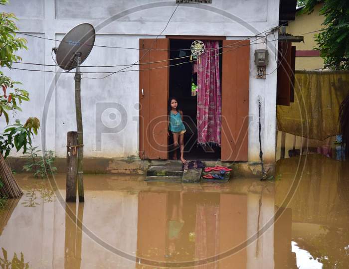 A girl stands near the door of her partially submerged house in a flood-affected village in Nagaon, Assam on July 22, 2020
