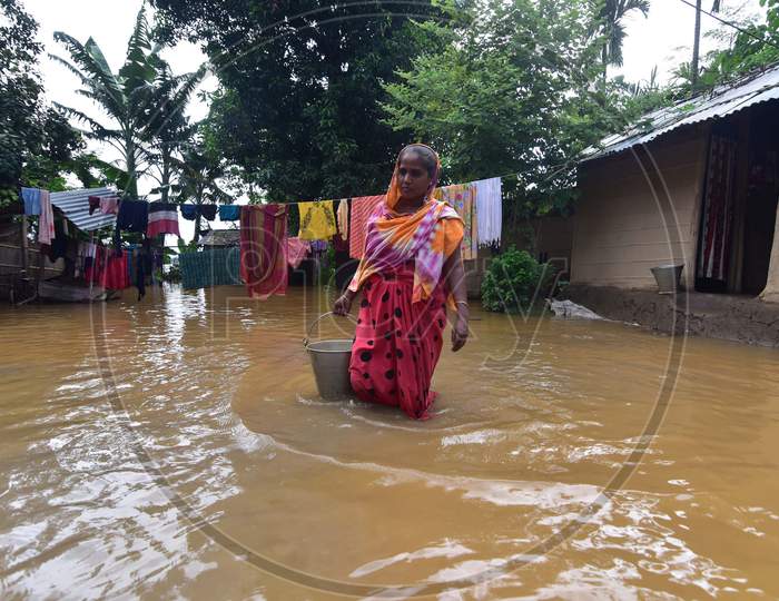 A woman carries a bucket of drinking water while she wades her way through the floodwaters in a flood-affected village in Nagaon, Assam on July 22, 2020