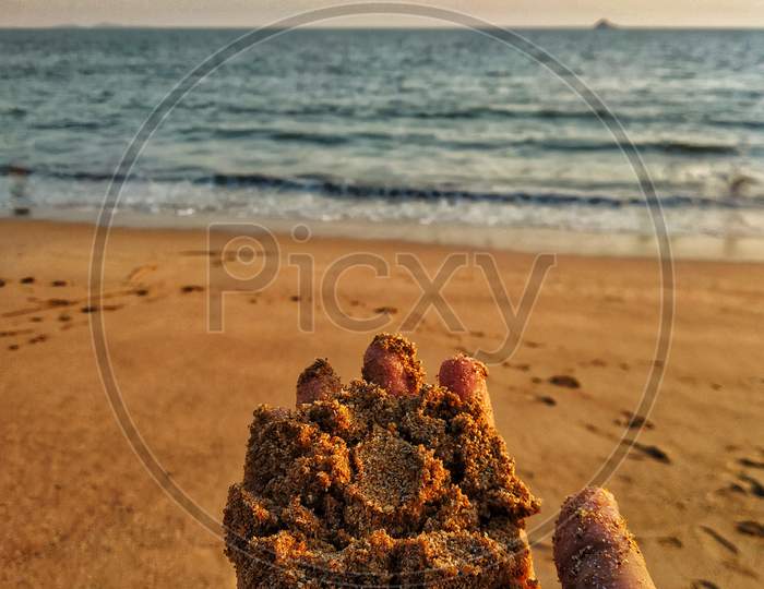 A Hand With Sand Of The Beach On The Beach.