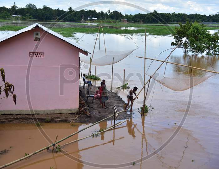 A man casts his fishing nets to catch fishes in the floodwaters near his partially submerged hut at a village in Nagaon, Assam on July 22, 2020
