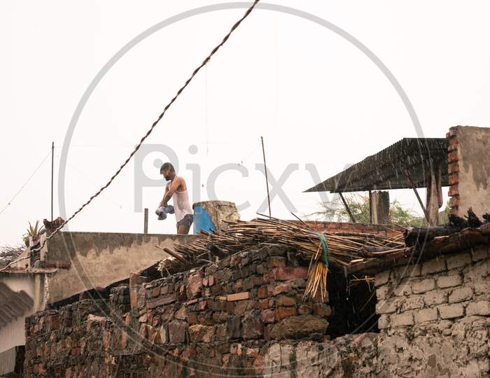 A person takes bath on a roof while it rains heavily during monsoon season