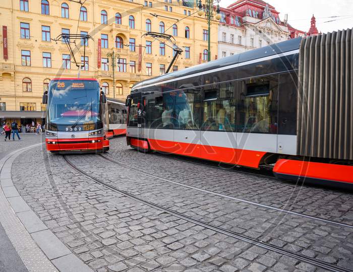Two Modern Electric Trams Passing Each Other As They Round A Corner On The Cobbled Streets Of The Old Town District Of Prague