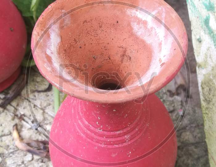 A Top Angle View Of A Vibrant Red Colored Earthen Pot In A Garden.