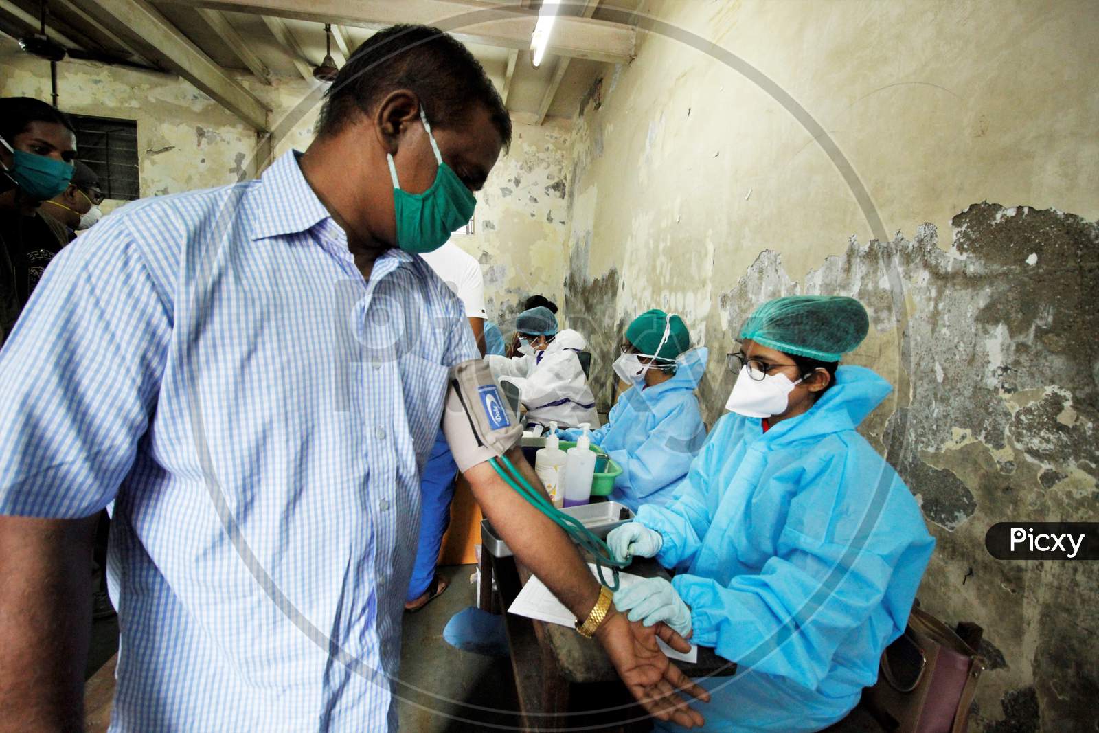 A healthcare worker checks BP of a recovered Covid-19 patient during screening for plasma donation, at a camp set inside a classroom of a school, at Dharavi, in Mumbai, India on July 23, 2020.