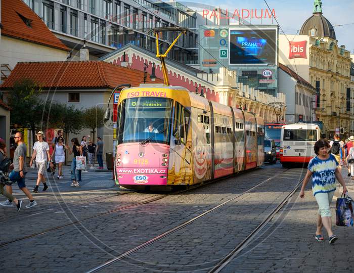 An Electric Tram Makes Its Way Between Old Buildings And Tourists On The Cobbled Streets Of The Old Town District Of Prague