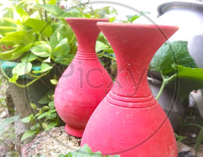 Two Earthen Pots Of Red Color Placed Outside In A Garden For Decoration And Beauty.
