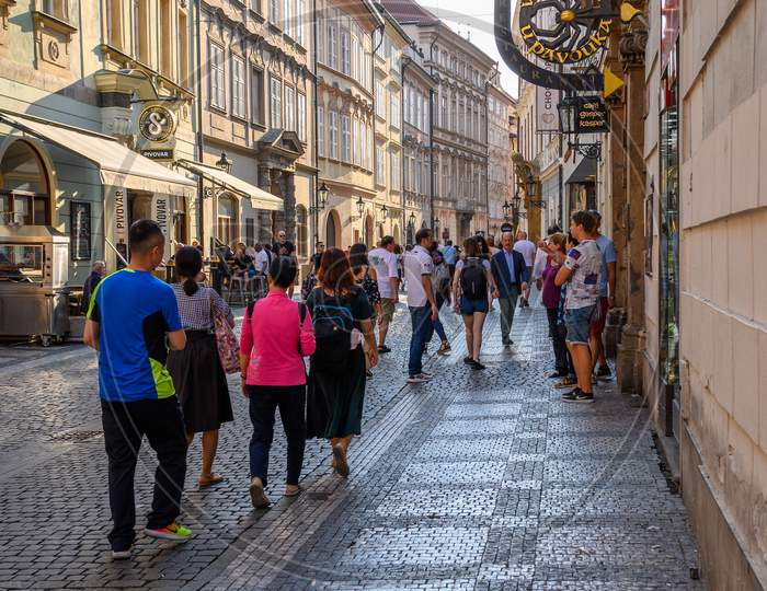 Vertical Shot Of A Crowded Tourist Cobbled Street Scene Between Old Shop Buildings In Prague, Czech Republic