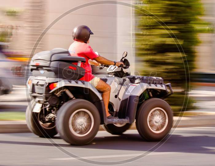 Malaga, Spain - September 04, 2015: Side View Of A Man Wearing Helmet And Riding Quadro Four Wheel Scooter Aka Quooder In Costa Del Sol