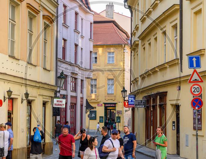 Tourists Crossing A Zebra Crossing On An Old Cobbled Street In Prague, Czech Republic