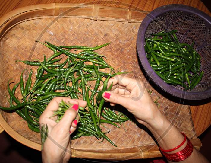Indian woman making green chilli and separating unwanted part of chilli