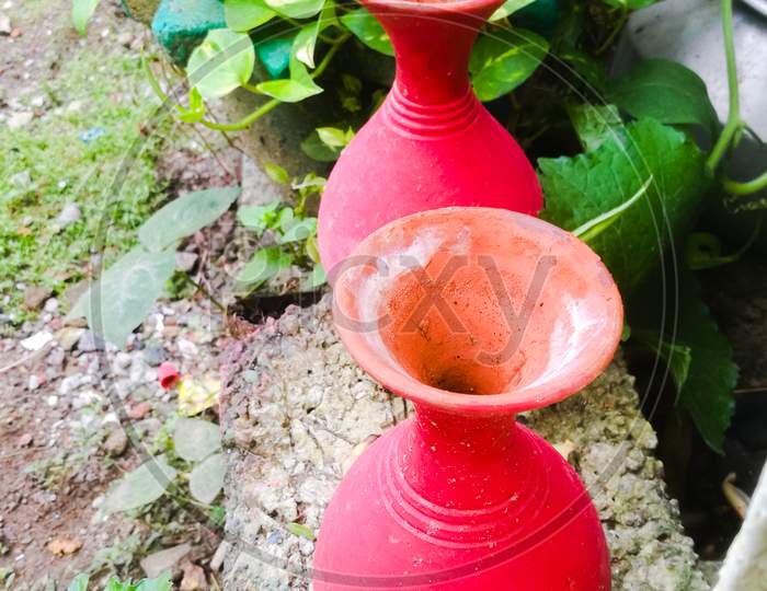Two Earthen Pots In Red Color Placed Side By Side In A Garden.