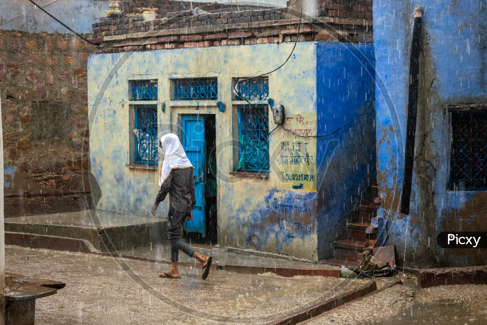 A man walks on a road while it rains heavily during monsoon season in Bharatpur