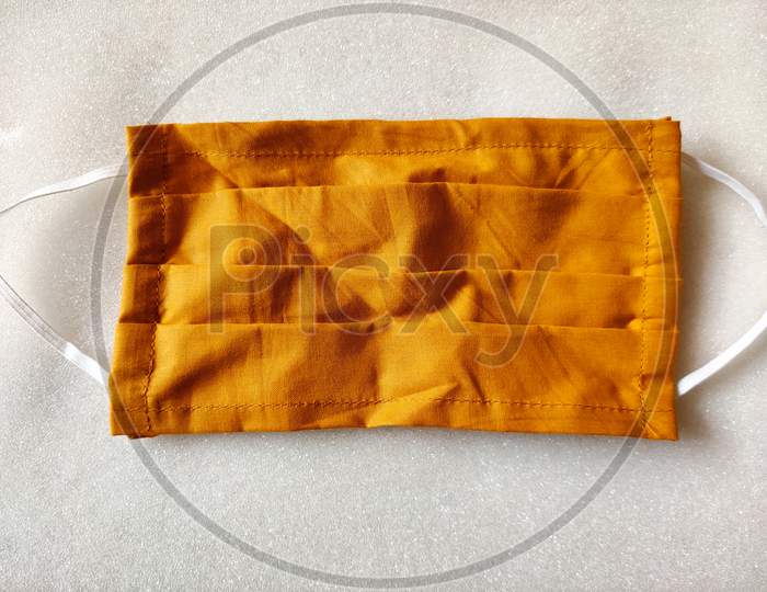A Orange Color Medical Type Face Mask Made Of Cloth Is Kept On White Background. Coronavirus Protection