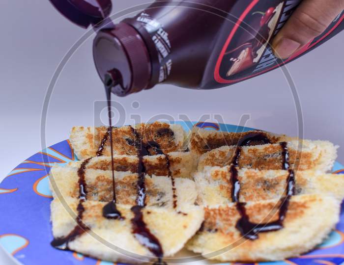 Pouring And Garnishing Hot Choco Lava Bread With Chocolate Syrup Or Sauce