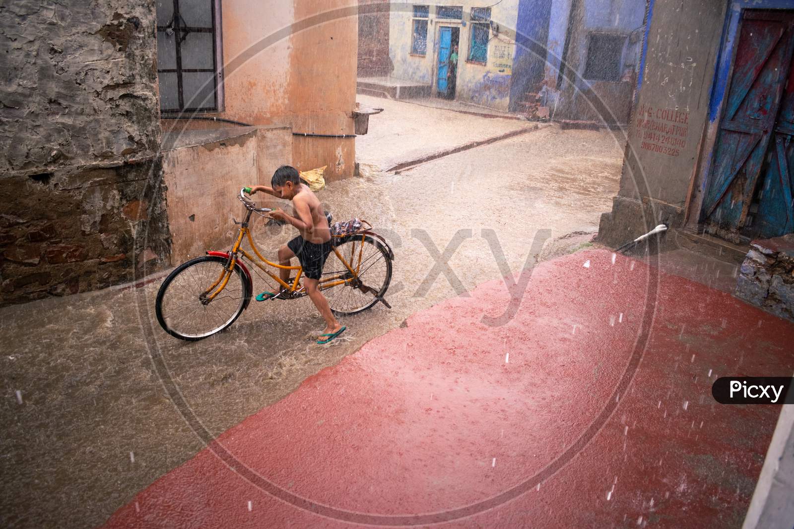 A boy riding bicycle and having fun in rain during monsoon in Bharatpur