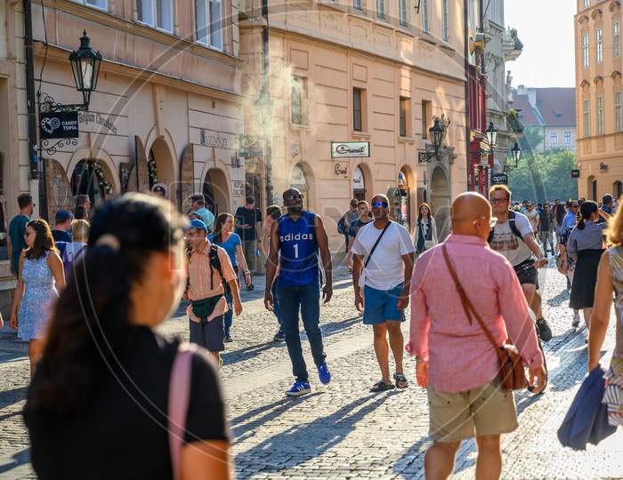 Tourists Exploring The Ancient Cobbled Streets In Old Town District Of Prague, Czech Republic In The Golden Light Of Early Evening
