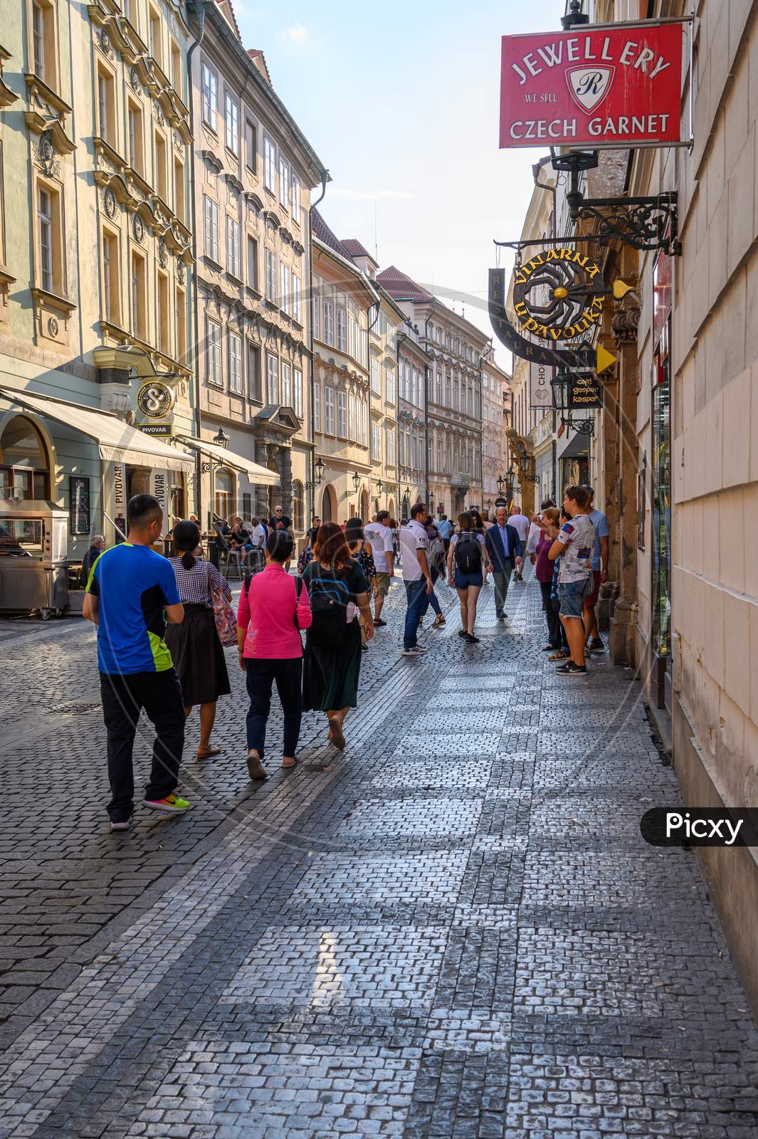 Vertical Shot Of A Crowded Tourist Cobbled Street Scene Between Old Shop Buildings In Prague, Czech Republic